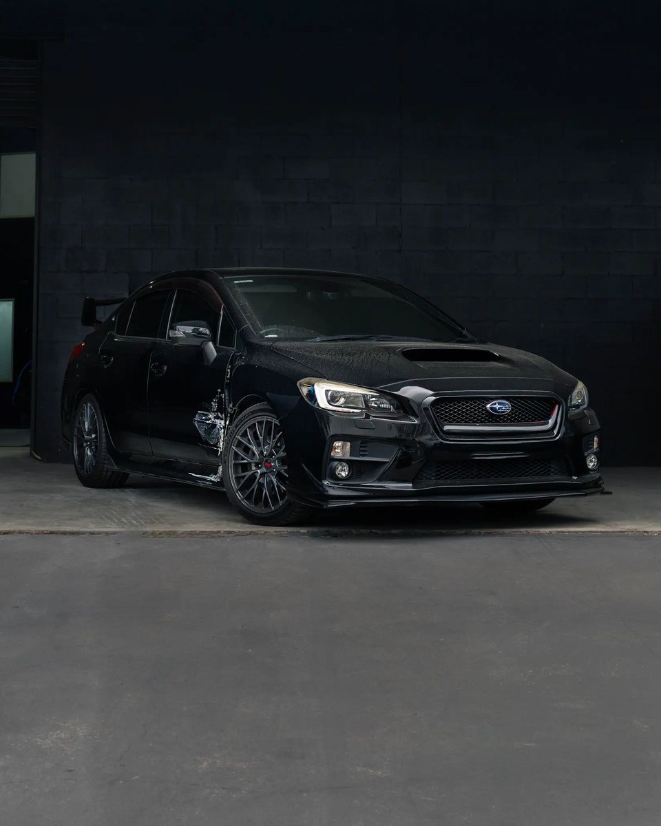 Full view of side impact damage on a black Subaru at Diverse Autobody