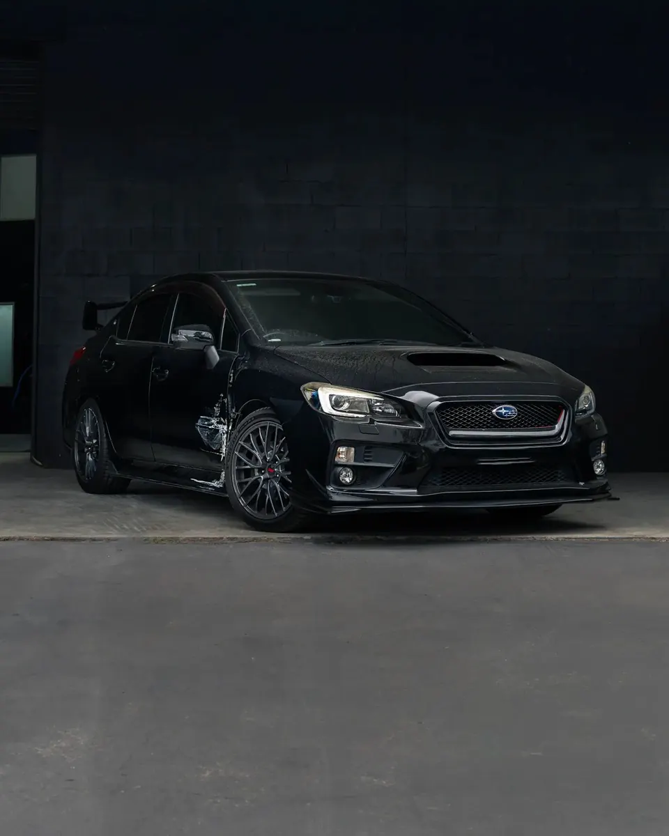 Full view of side impact damage on a black Subaru at Diverse Autobody